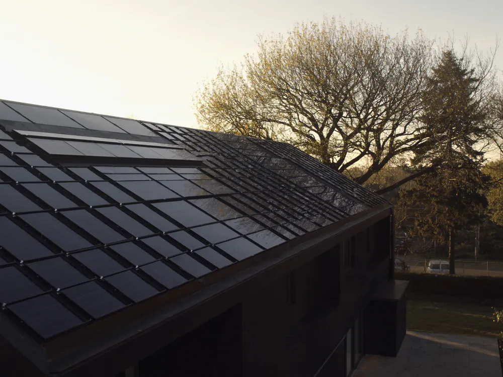 Hausdach vollständig mit schwarzen Solarmodulen belegt, Morgenlicht